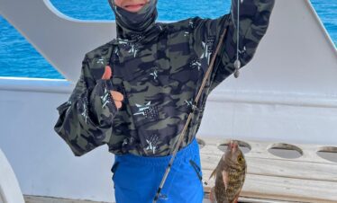 Touriste tenant une canne à pêche avec un poisson pris en mer, à bord du yacht.