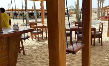 Restaurant de plage avec balançoires et bar, installé sur le sable.