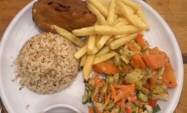 Une assiette garnie avec frites, riz, cordon bleu ou poisson pané, et légumes sautés.