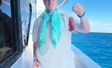 Touriste tenant une canne à pêche avec un petit poisson pris en mer, à bord du yacht.
