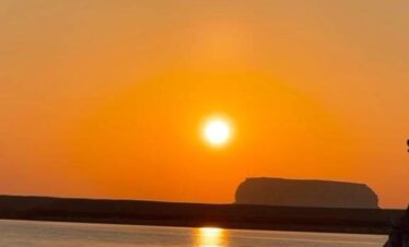 Vue sur le Nil au coucher du soleil depuis une felouque à Louxor, avec des reflets dorés sur l’eau.