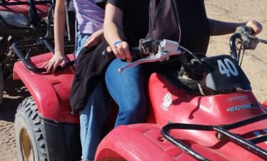 Deux touristes sur un quad dans le désert d'Hurghada, avec d'autres quads en arrière-plan.