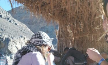 Touristes dégustant du thé traditionnel sur un tapis bédouin dans le désert.