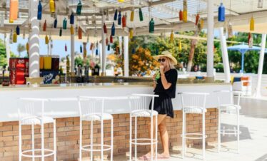 Bar extérieur de l’hôtel en journée avec une touriste dégustant un cocktail.