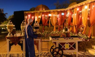Restaurant extérieur de nuit avec chariots traditionnels et serveur en tenue locale.