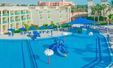 Piscine pour les tout-petits avec transats, parasols, une partie de l’hôtel et des palmiers en arrière-plan.