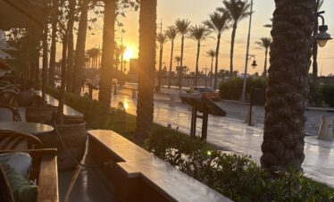 Restaurant extérieur de l'hôtel Sindbad Club 4* avec vue sur la route et les palmiers.