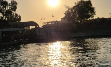 Vue sur le Nil au coucher du soleil depuis une felouque à Louxor, avec des reflets dorés sur l’eau.