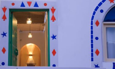 Porte nubienne ouverte avec luminaires suspendus, niche lumineuse et décoration traditionnelle bleu et orange.