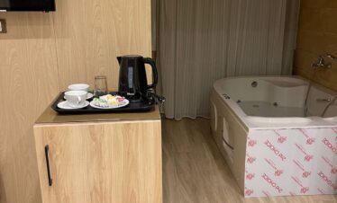 Chambre en bois avec jacuzzi, mini-frigo dissimulé, plateau de courtoisie et télévision murale.