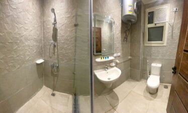 Salle de bain moderne avec carrelage effet pierre, douche à l'italienne et lavabo classique.