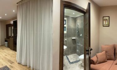 Chambre moderne avec une touche de confort rose et un canapé accueillant, offrant une salle de bain raffinée.