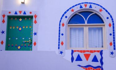 Façade avant de la maison d'hôte Jareedy à Assouan, murs blancs avec décoration nubienne, porte et fenêtre d'entrée.