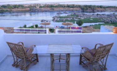Terrasse d'une des chambres de la maison d'hôte Jareedy à Assouan, vue sur le Nil avec chaises et table en osier.