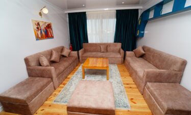 Salon intérieur d’un Dahabiya avec canapés camel, décoration nubienne et vue sur le Nil.