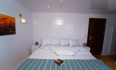 Chambre double minimaliste avec grand lit, tables de chevet et décoration épurée.