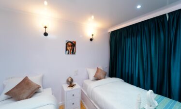 Chambre lumineuse avec deux lits simples à bord d’un bateau Dahabiya en Égypte.