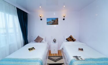 Chambre lumineuse avec deux lits simples à bord d’un bateau de croisière, décoration élégante et épurée, idéale pour un séjour confortable sur le Nil.