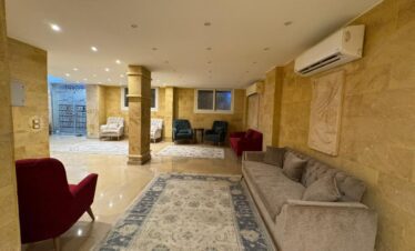 Hall spacieux avec canapés en velours, décoration murale en pierre marron-beige.