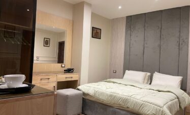 Chambre élégante avec mobilier moderne et une touche de confort avec son mini-frigo et son lit en velours gris.