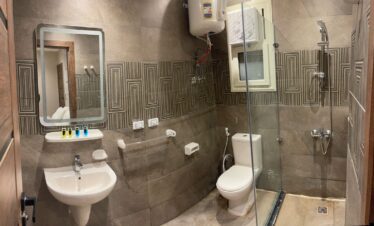 Salle d'eau moderne en carrelage gris avec fresque décorative, lavabo design et toilettes.